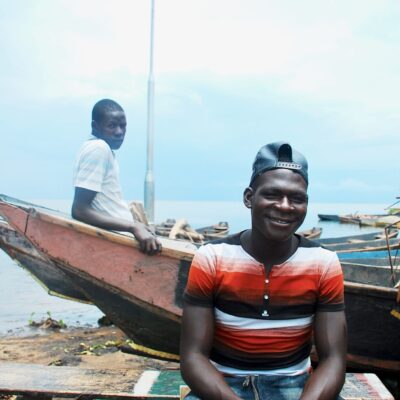 Taylor Coyne - In Waiting - Lac Kyoga (Ouganda), 2018 - Being able to tap into the regional fish market would help Lake Kyoga’s fishers, like these two, rely less on diminishing fish stocks and so see their finances grow. For many of the fishers, better livelihoods mean having food on the table. In 2017, over 1000 students from schools around the northern shore of Lake Kyoga stopped attending classes in order to start fishing on the lake. Mr. Ongu, the Sub-country chairperson for one of these districts told a local newspaper, "Some children are saying government should not deny them access to the lake because they cannot study on empty stomachs. They say the government should shut down all the schools in the area”. With falling fish stocks and prolonged dry seasons the area has been heavily impacted by on-going food shortages, with many families surviving off relief food from the government.